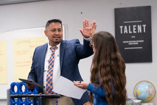 A young student gives a high-five with her instructor
