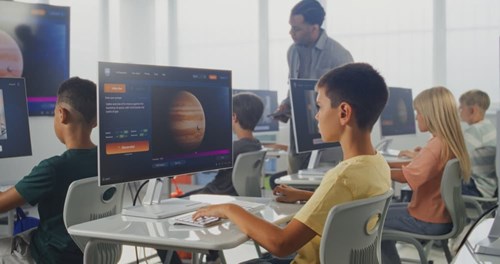 Elementary school students work on their computer creating an AI video of the solar system